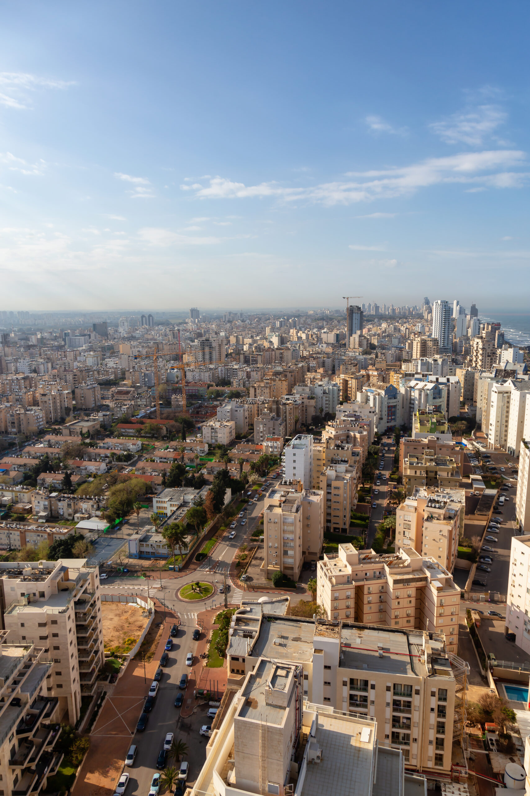 Aerial view of a residential neighborhood in a city during a cloudy and sunny sunrise. Taken in Netanya, Center District, Israel.